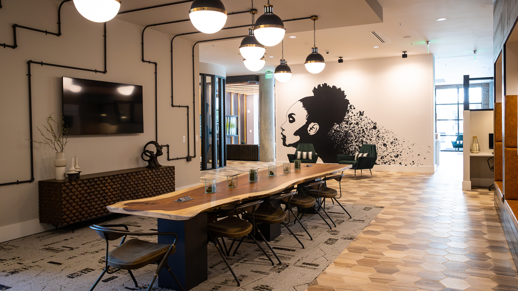 a long communal table in a room with chairs and a wall with a mural