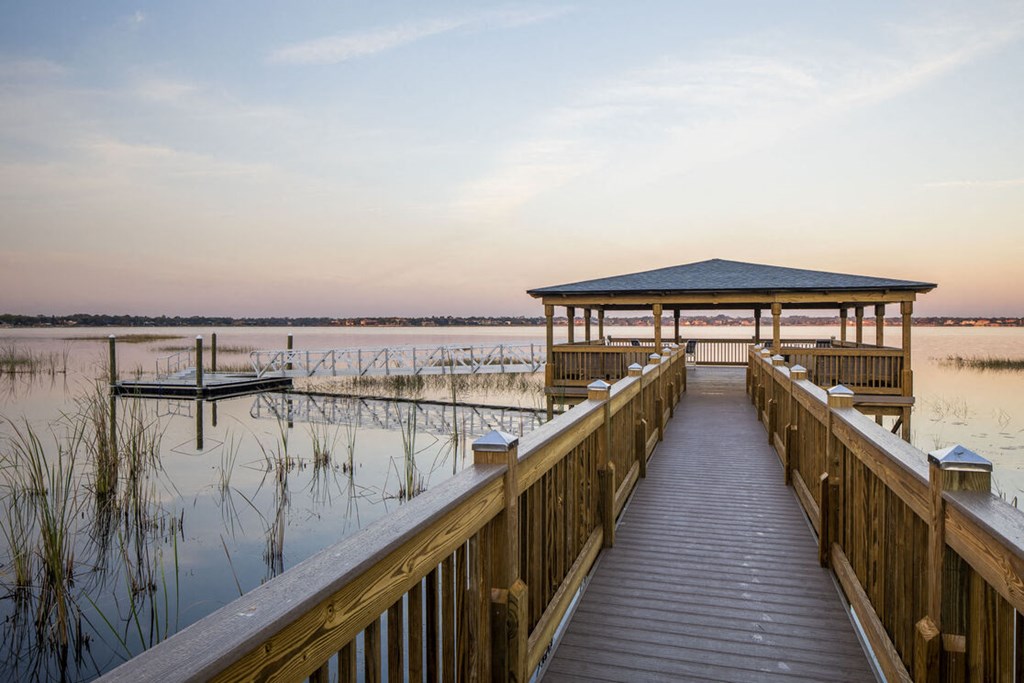 a dock with a gazebo on the water at sunset
