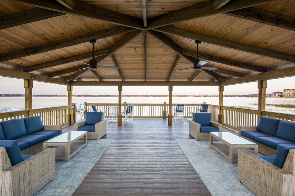 a porch with couches and tables and a view of the water