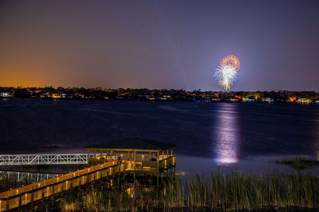fireworks over the water at night over a dock on a lake