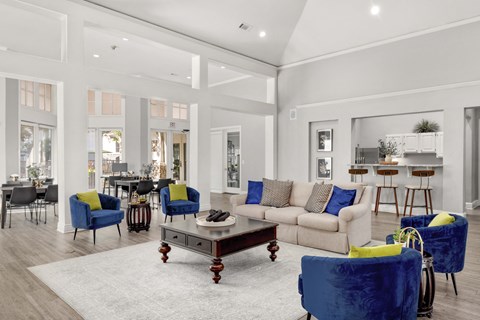 A living room with a white couch, blue chairs, and a coffee table.