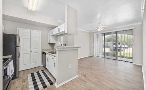 A kitchen with white cabinets and a black and white checkered rug.
