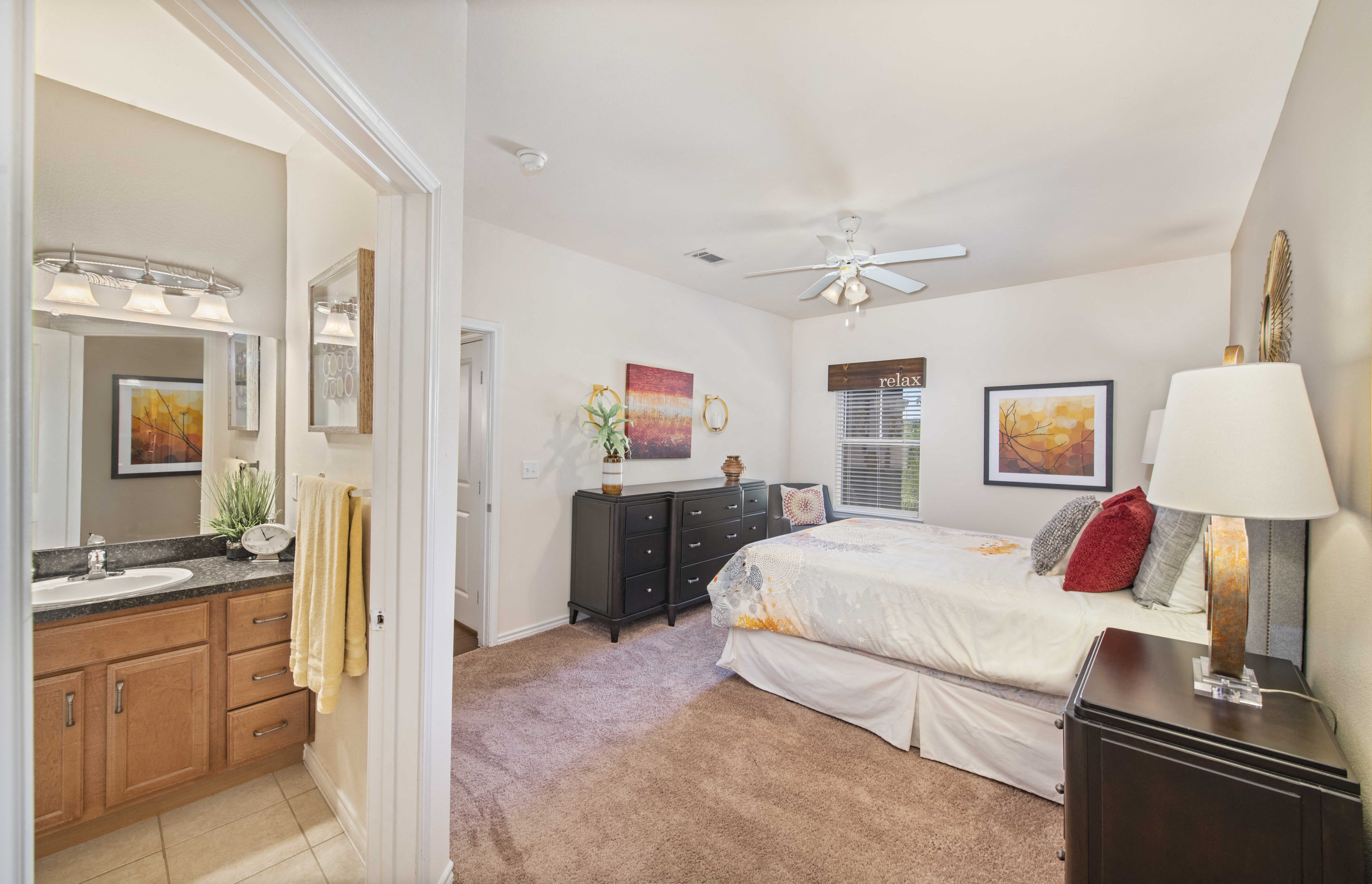 A bedroom with a bed, dresser, and a ceiling fan.