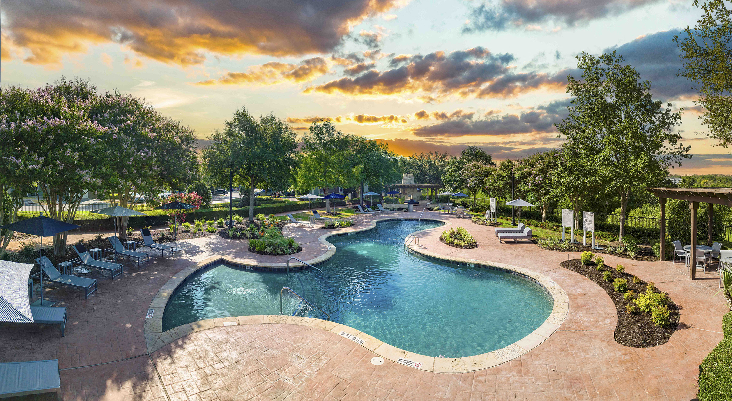 A large outdoor swimming pool surrounded by a patio and trees.
