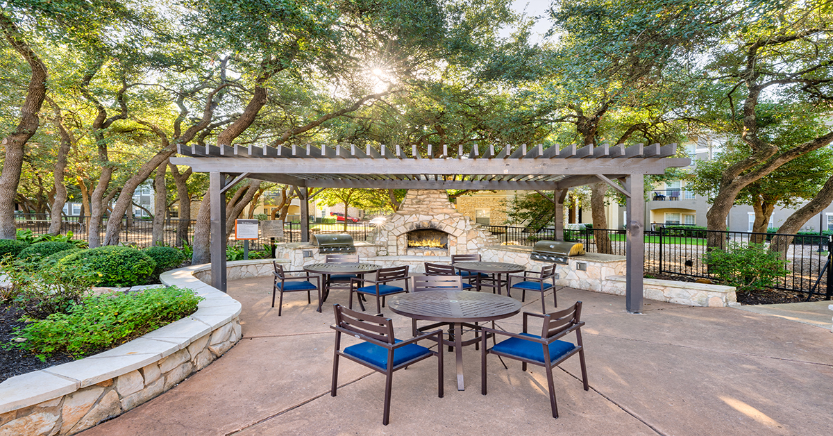 A patio with a table and chairs under a pergola.
