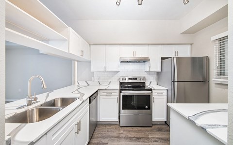 a kitchen with white cabinets and stainless steel appliances