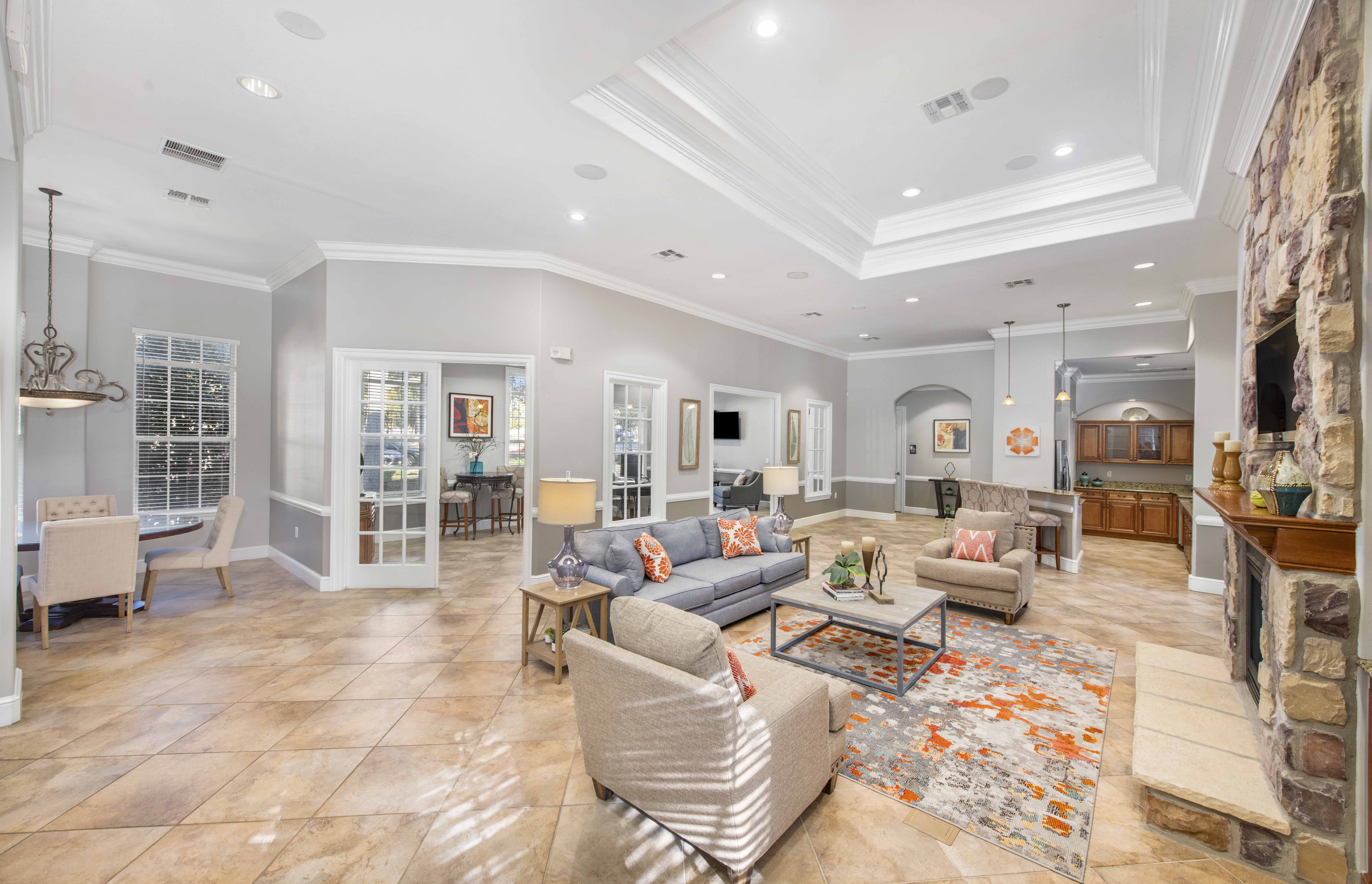 A spacious living room with a stone fireplace and a large rug.