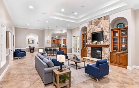 A living room with a stone fireplace and a grey couch.
