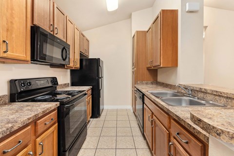 A kitchen with black appliances and wooden cabinets.