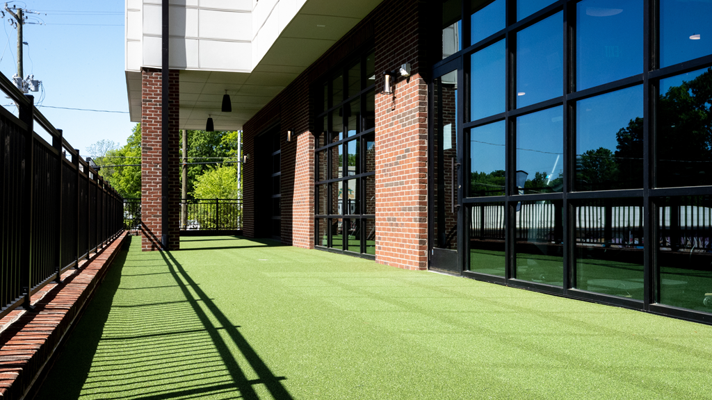 a green walkway outside a building with black windows