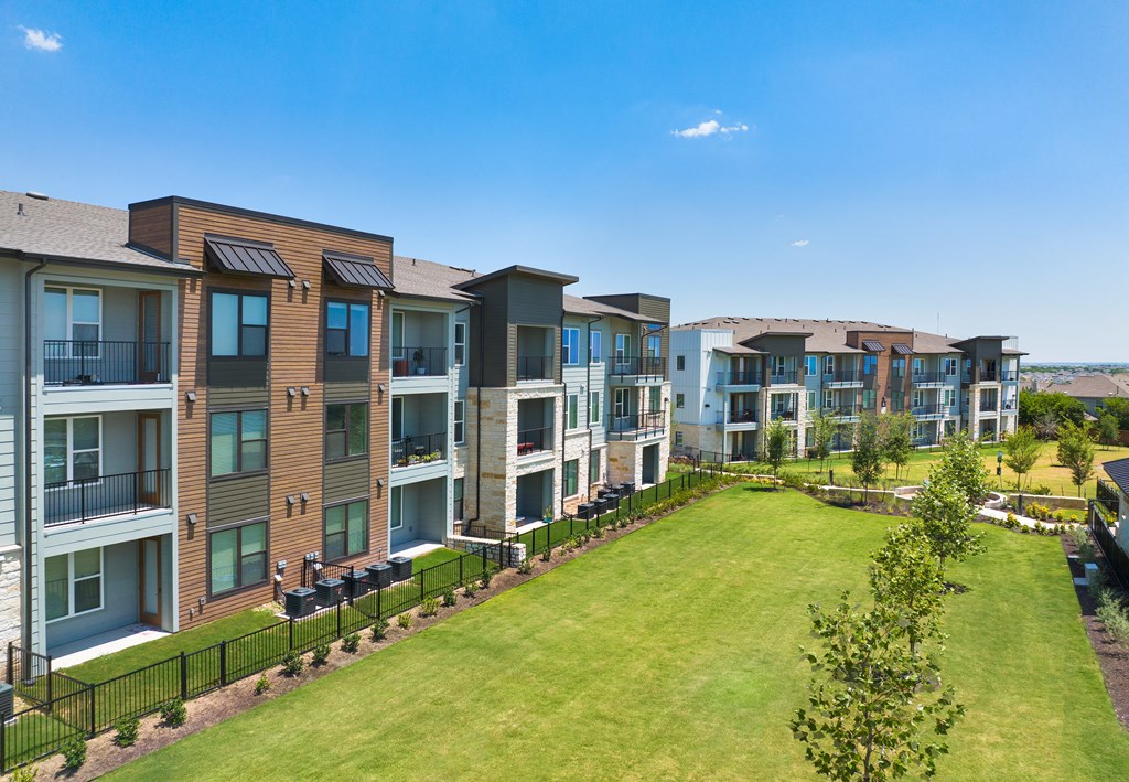 an exterior view of an apartment building with a green lawn
