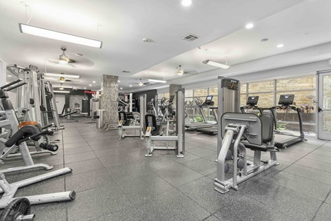 A gym with a variety of equipment including treadmills, weights, and exercise machines.