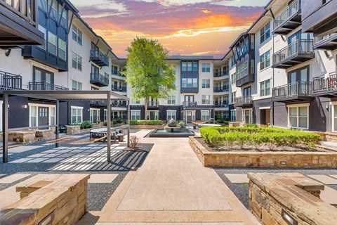 A courtyard surrounded by apartment buildings with a tree in the middle.