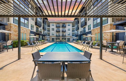 A large outdoor pool area with a table and chairs.