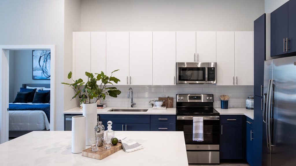 a modern kitchen with blue and white cabinets and stainless steel appliances