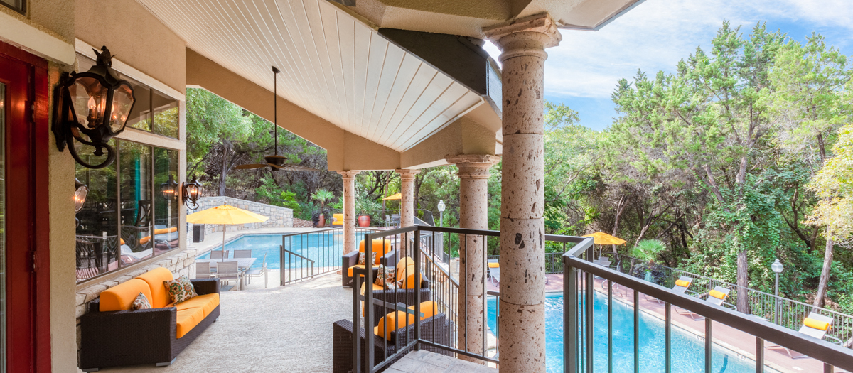 A balcony with a pool and trees in the background.