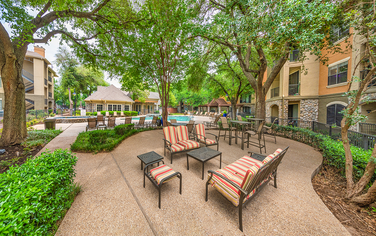A patio with chairs and a table surrounded by trees.