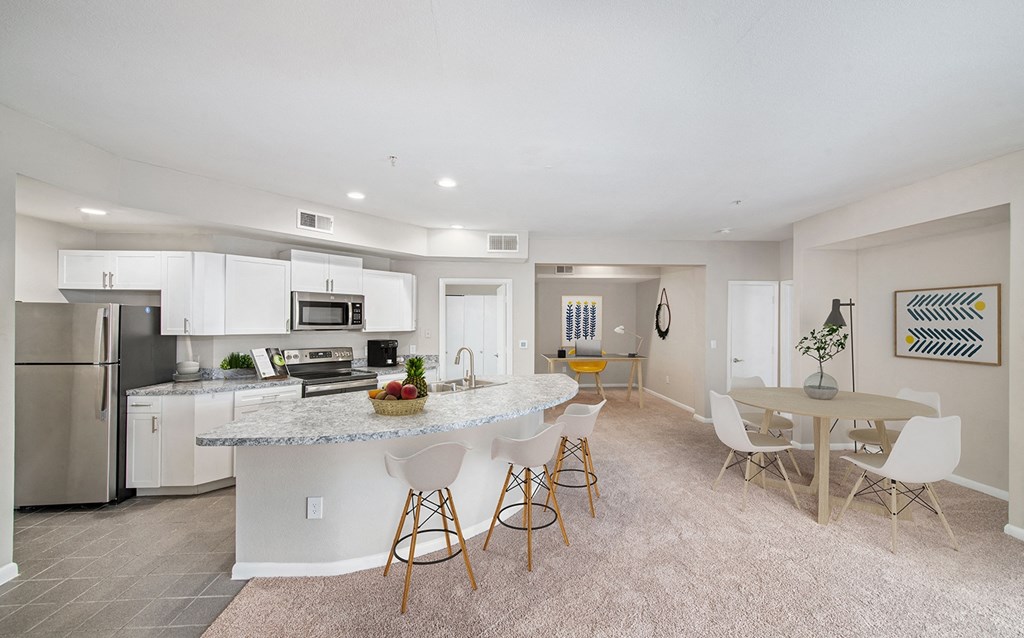 an open kitchen and dining area with a marble counter top and stainless steel appliances