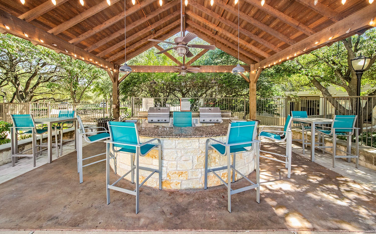 A patio with a table and chairs under a wooden roof.