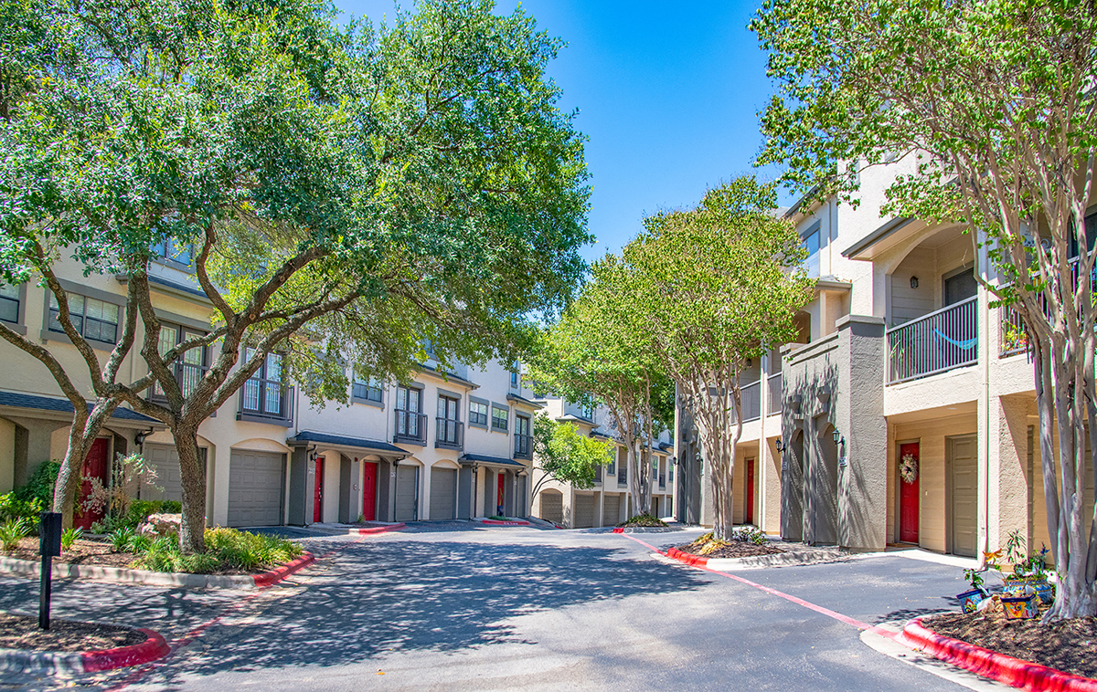 A tree-lined street in front of apartment buildings.