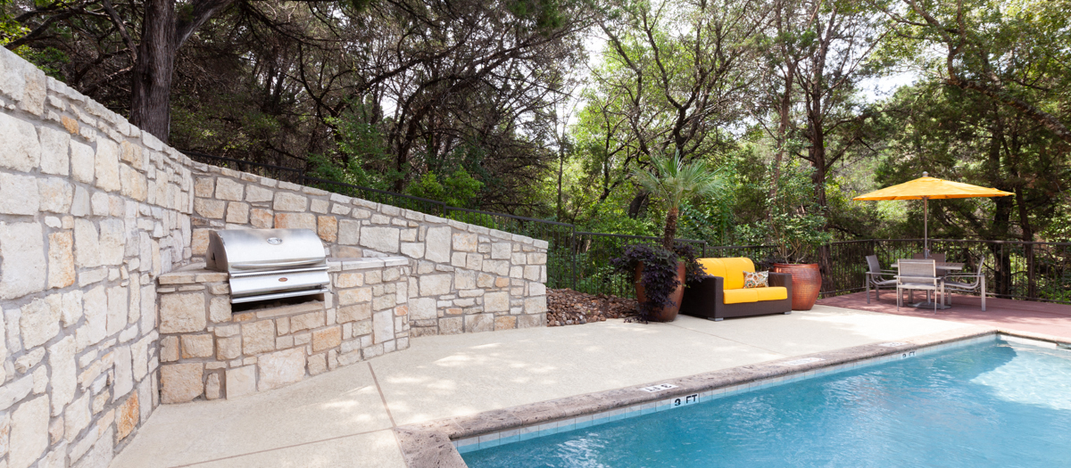 A pool with a stone wall and a yellow chair.