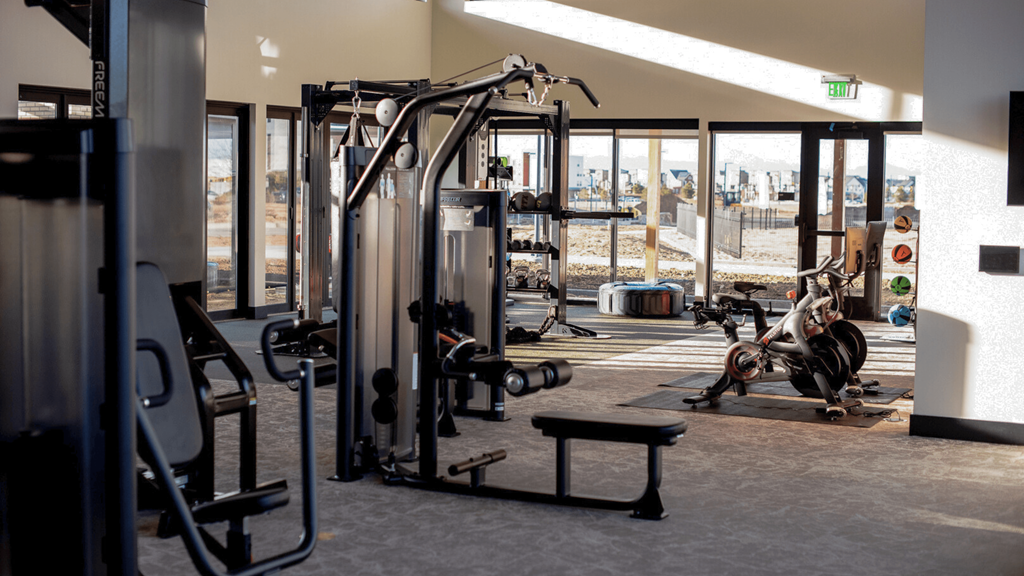 a gym with weights and cardio equipment and a view of a construction site