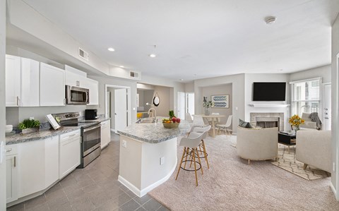 a kitchen and living room with white cabinets and a counter top