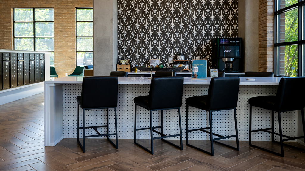 a bar with bar stools in front of a counter with chairs