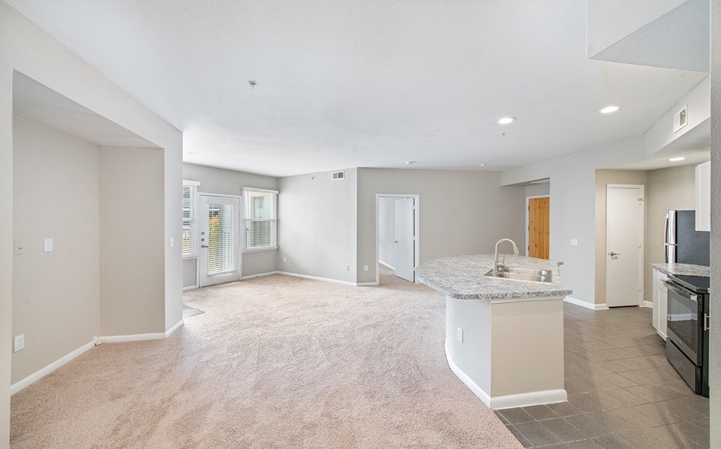 an empty living room and kitchen with a granite counter top