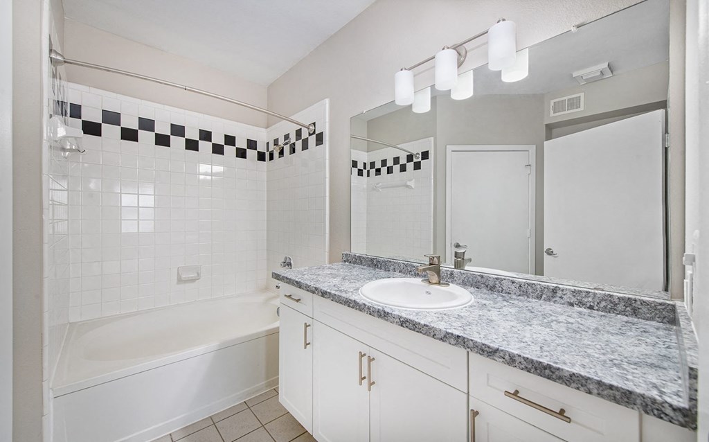 a bathroom with a sink and a tub and a mirror