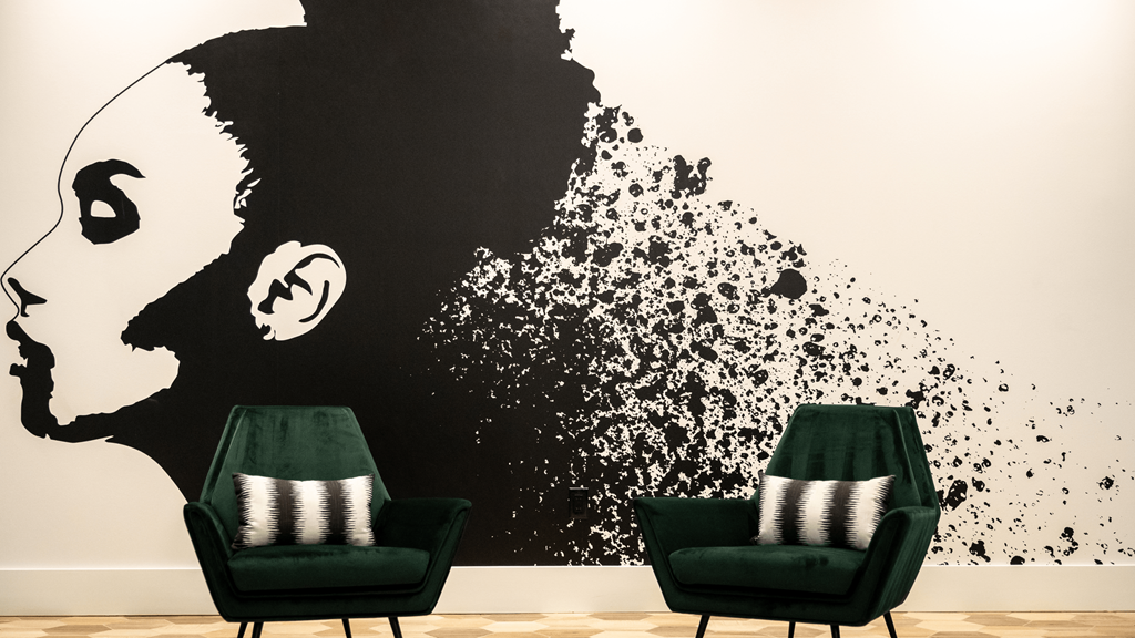 a pair of green chairs in front of a wall with a black and white mural