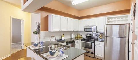 A kitchen with white cabinets and stainless steel appliances.