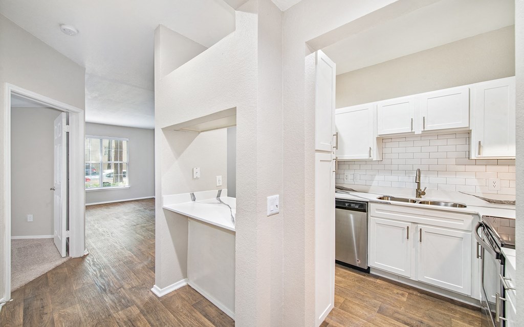 an open kitchen and living room with white cabinets