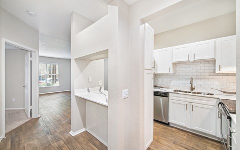 an open kitchen and living room with white cabinets