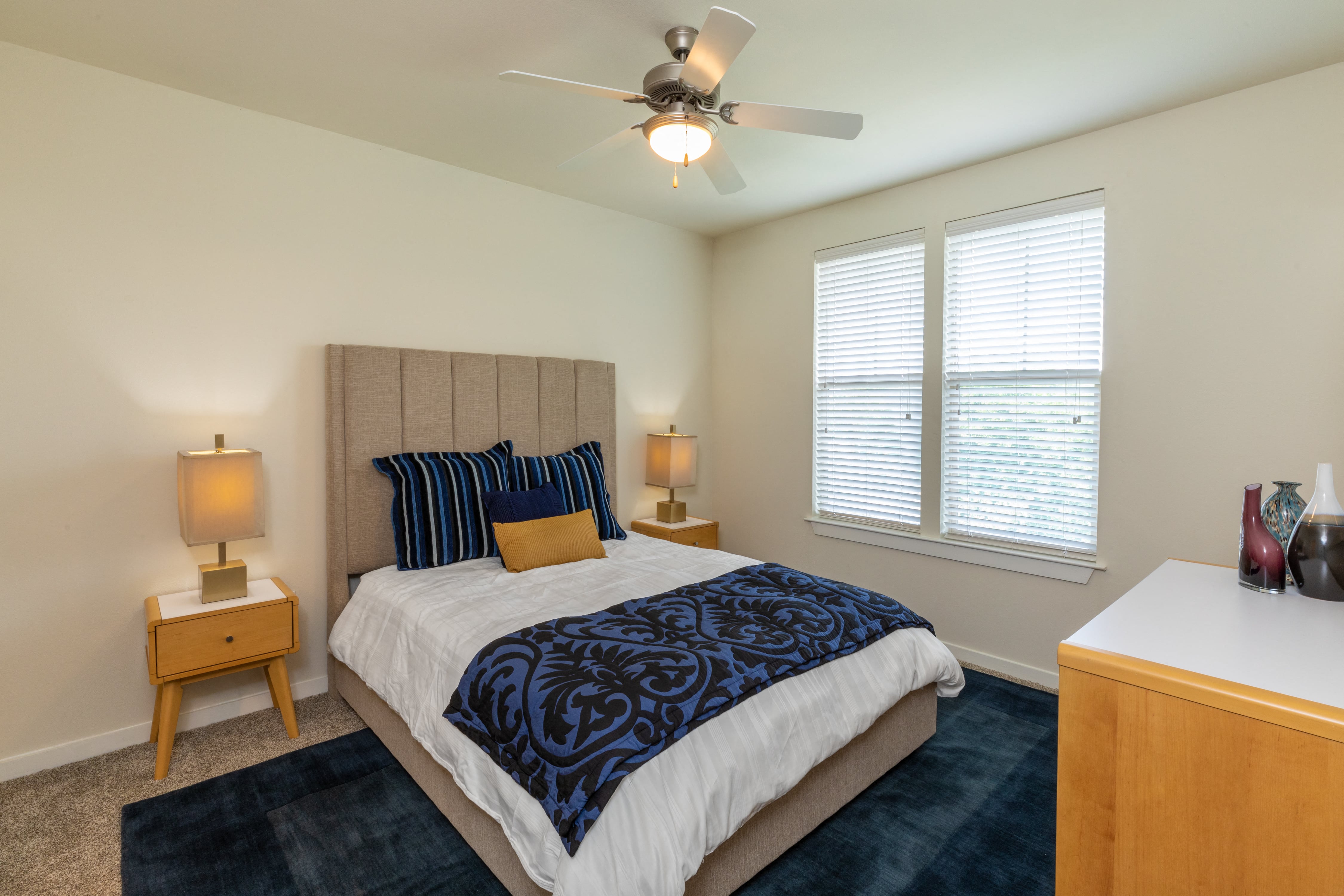 A bedroom with a bed, nightstands, and a ceiling fan.