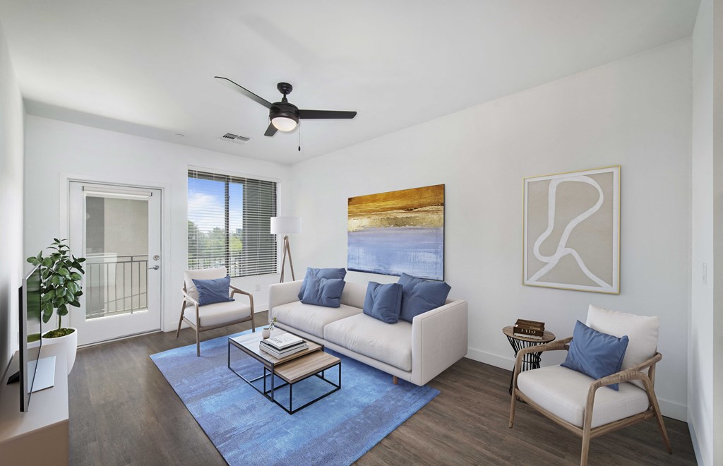 a living room with a couch and two chairs and a ceiling fan