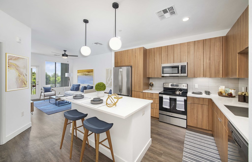 an open kitchen and living room with an island and stools