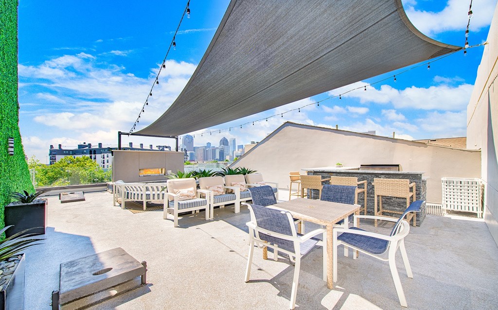 a rooftop patio with tables and chairs and a city in the background