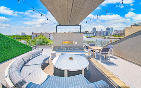 a rooftop terrace with couches and a table and a fireplace