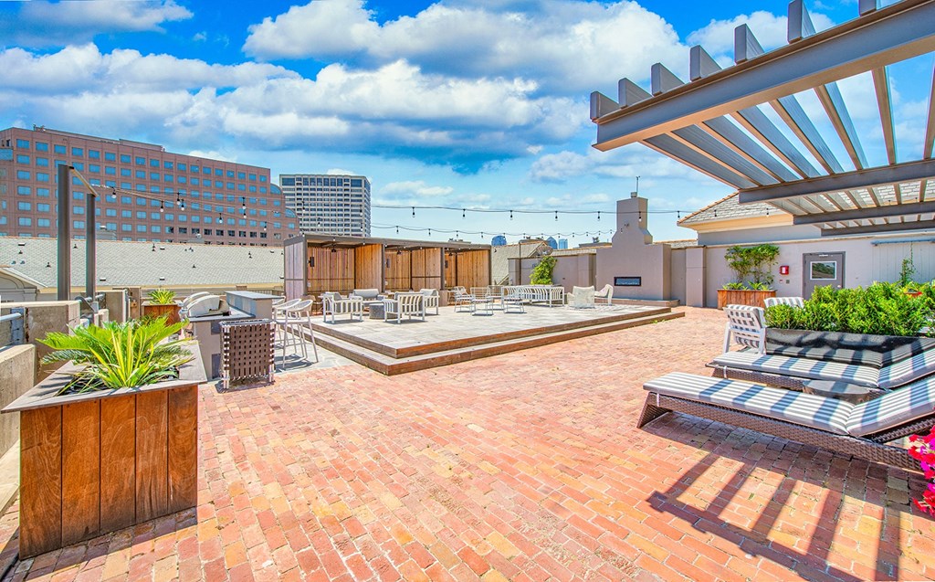 a rooftop patio with benches and chairs and a city in the background