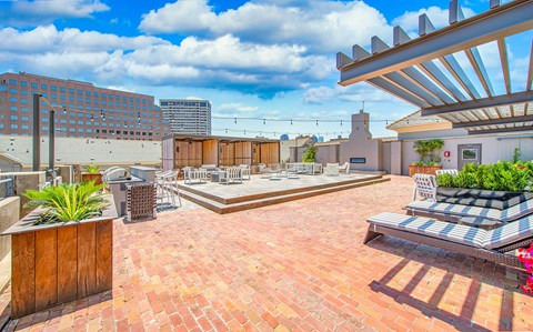 a rooftop patio with benches and chairs and a city in the background