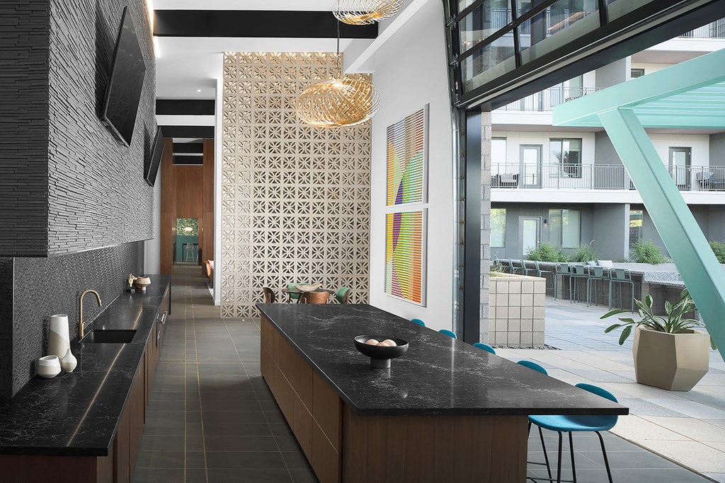 a long kitchen with black counter tops and a large window