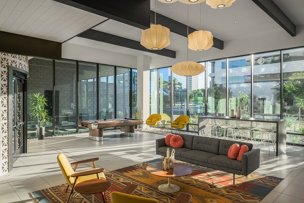 a living room with large windows and a couch and tables