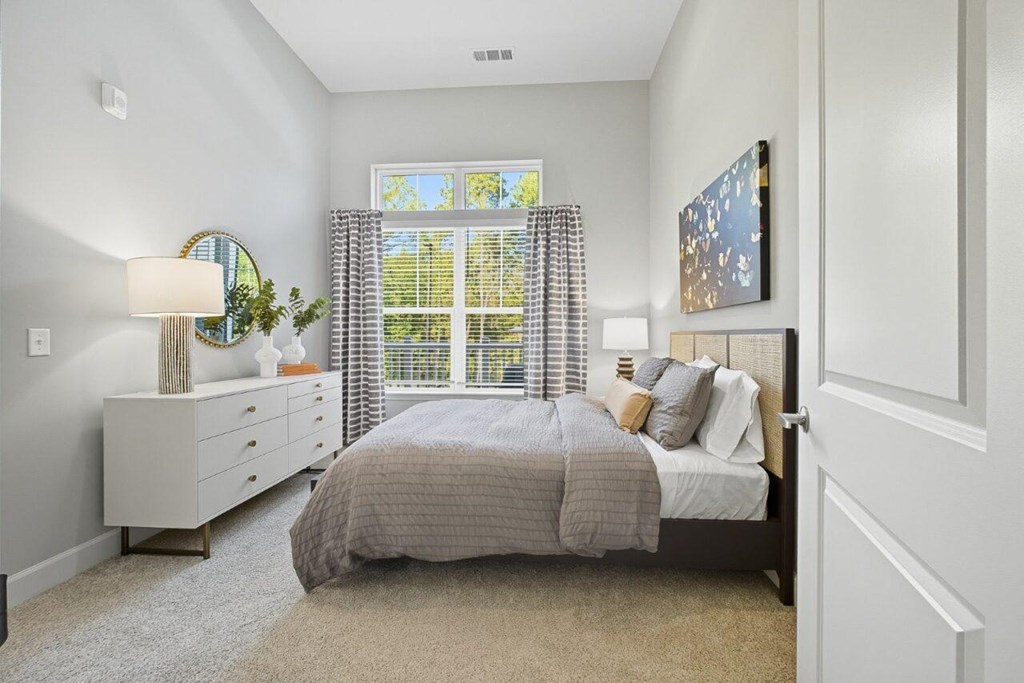 A bedroom with a bed, nightstand, and window.