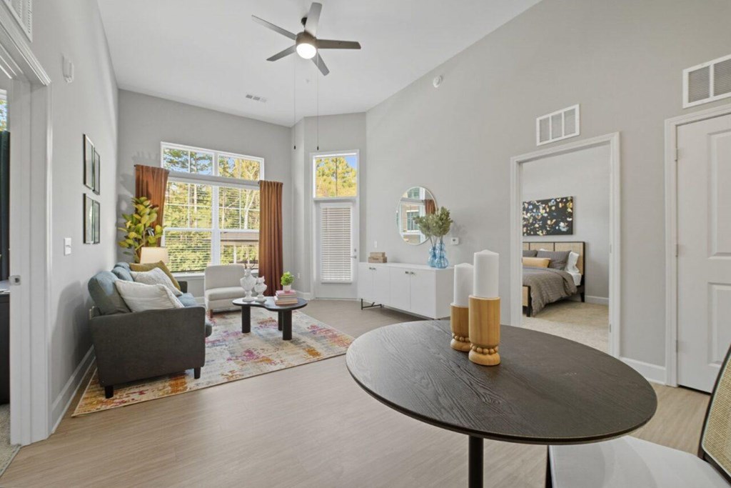 A living room with a grey couch, a black table, and a ceiling fan.