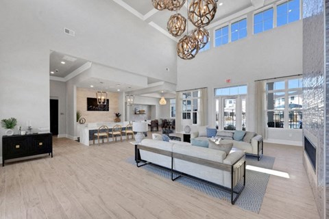 A spacious living room with a large grey sofa and a wooden floor.