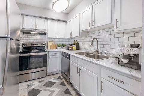 Kitchen, wood-like flooring, stainless steel appliances, white cabinets, extended sink
