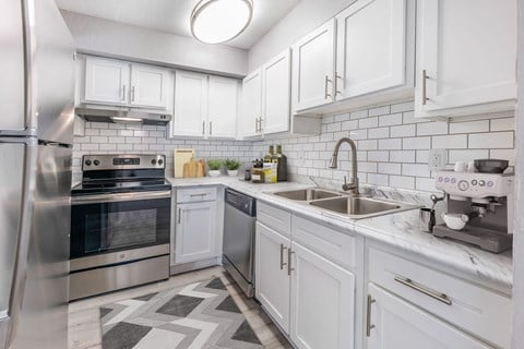 Kitchen, wood-like flooring, stainless steel appliances, white cabinets, extended sink
