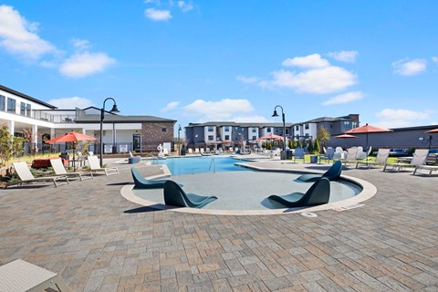 Resort-style swimming pool with sundeck and lounge seating at Argento at the Bridges apartments in McDonough GA