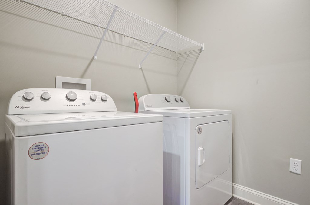 laundry room has full size washer and dryer with shelving behind it
